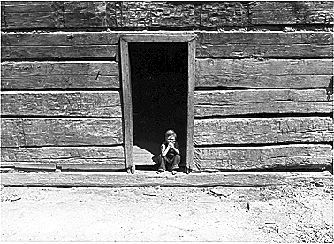 Photo of young
boy in log cabin doorway